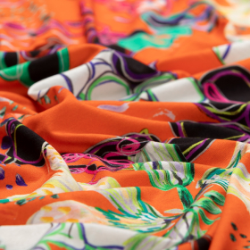 oranje stretch tricot stof met ecru, groen, zwart abstracte bloemen Italiaans import