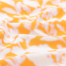 oranje crepe viscose stof met ecru, licht roze bloem dessin